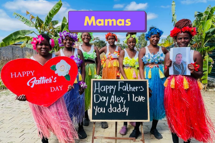 Group of African women in colorful dresses with a Father's Day sign and heart-shaped card for a greeting video